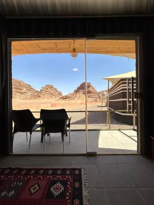 a patio with a view of the desert through a sliding glass door at Gem wadi rum camp in Wadi Rum