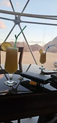 two glasses on a table with a view of the desert at Rum Plaza Luxury Camp in Wadi Rum