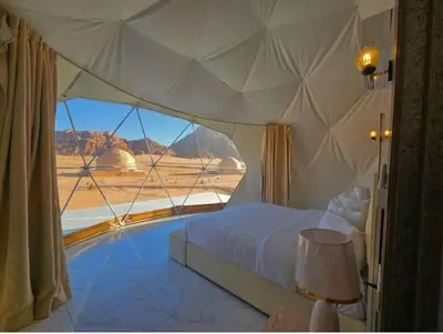 a bedroom with a bed and a large window at Rum Plaza Luxury Camp in Wadi Rum