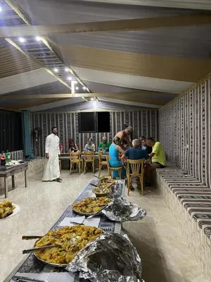 a group of people sitting at tables with pizzas at Mira Bedouin Camp in Wadi Rum