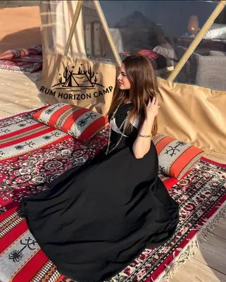 a woman in a black dress sitting on a bed at Rum Horizon Bubble luxury camp in Wadi Rum