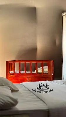 a bed with a wooden headboard in a room at Rum Horizon Bubble luxury camp in Wadi Rum