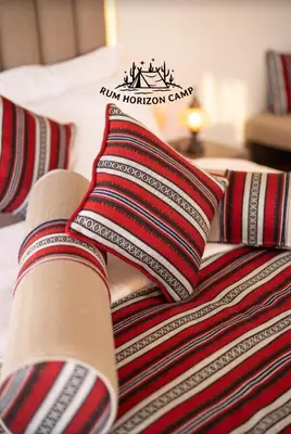 a bed with red and black pillows on it at Rum Horizon Bubble luxury camp in Wadi Rum