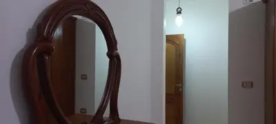 a bathroom mirror with a wooden frame on a wall at Khalda Apartments for females in Amman