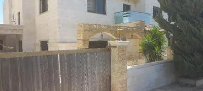 a fence in front of a building with a house at Khalda Apartments for females in Amman