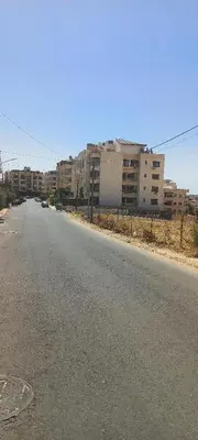 an empty street with buildings in the background at Khalda Apartments for females in Amman