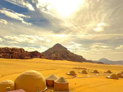 a group of domes in the desert with a mountain at Wadi Rum Marina Camp in Wadi Rum