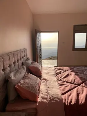 a bedroom with a bed with pillows and a window at مزرعة الشفق in Ad Dimnah