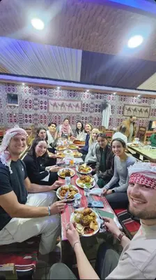 a group of people sitting at a long table eating food at Madar Camp, Wadi Rum in Wadi Rum