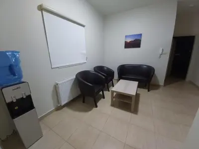 a waiting room with black chairs and a table at CMK Housing in Madaba