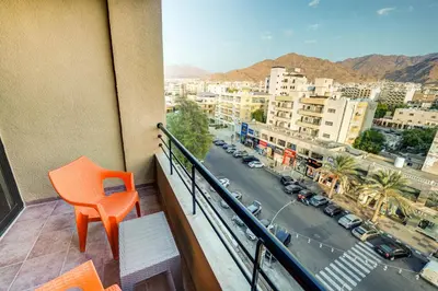 a balcony with an orange chair and a view of a city at The Loft hotel By FHM in Aqaba