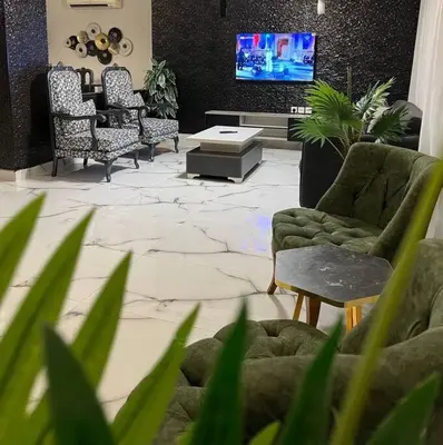 a living room with chairs and a tv and a table at Luxury 4-bedrooms apartment in Aqaba