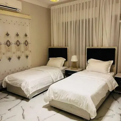 two beds in a bedroom with white sheets and pillows at Luxury 4-bedrooms apartment in Aqaba