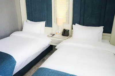 two white beds in a room with a telephone at Rival Hotel Amman in Amman