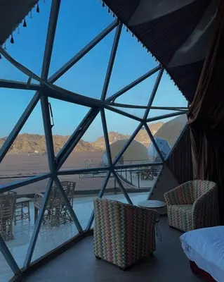 a room with a view of the desert from a glass wall at Wadi Rum Santa Camp in Wadi Rum