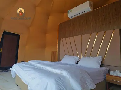 a bedroom with a large bed with white sheets at wadi rum,Linda Camp in Wadi Rum