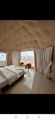 a bedroom with a large bed and a large window at Joker camp Wadi Rum in Disah