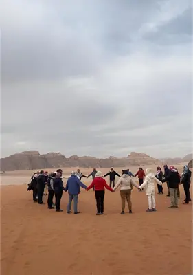 a group of people holding hands on the beach at The bubble camp in Wadi Rum