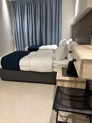 a bedroom with a bed with white sheets and a table at Aladnan hotel in Aqaba