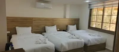 three beds in a hotel room with white sheets at Petra Desert Hotel in Wadi Musa