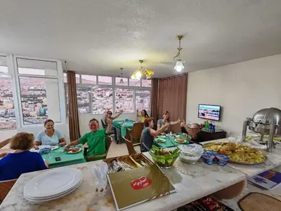 a group of people sitting around a table with food at iHome Petra in Wadi Musa