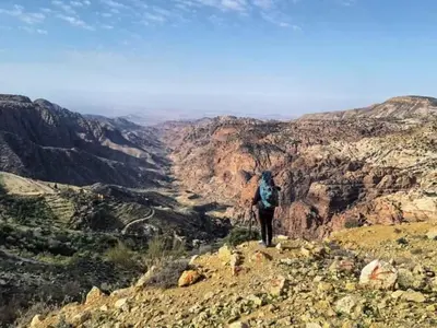 a person with a backpack standing on top of a mountain at - Trekking from Dana to Petra in Dana