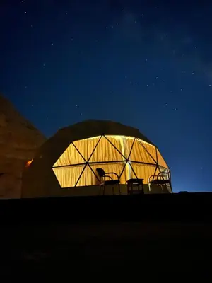 a dome tent with two chairs in it at night at SARAB Luxury Camp in Wadi Rum