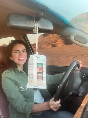a woman sitting in a car with a box hanging from the steering wheel at SARAB Luxury Camp in Wadi Rum