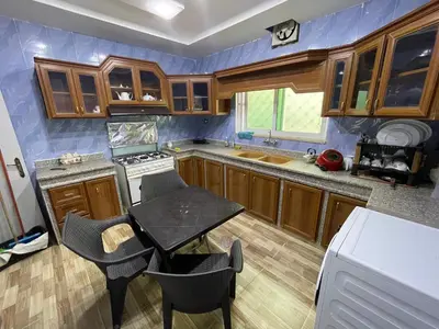 a kitchen with wooden cabinets and a table with chairs at Oskar Appartment in Wadi Musa