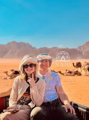 a man and woman sitting on a camel in the desert at Najd Luxury Camp in Wadi Rum