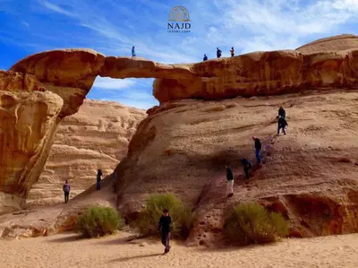 a group of people walking through an arch in the desert at Najd Luxury Camp in Wadi Rum