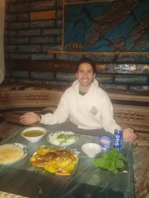 a man sitting at a table with food at Petra Musa Rural House in Wadi Musa
