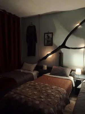 a hotel room with two beds and a branch on the wall at Petra Musa Rural House in Wadi Musa