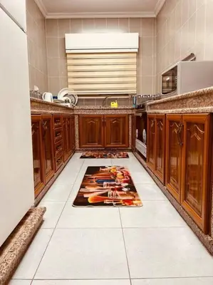 a kitchen with wooden cabinets and a rug on the floor at Lovely 3 bedrooms rental unit in Aqaba