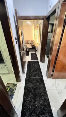 a hallway with black marble flooring and a living room at شقة مفروشة بغرفتي نوم الجاردنز in Umm Uthainah