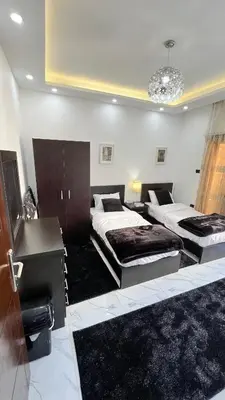 a bedroom with two beds and a piano in it at شقة مفروشة بغرفتي نوم الجاردنز in Umm Uthainah