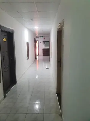 an empty hallway in a building with a door and a tile floor at Alfares Hotel in At-Tafilah