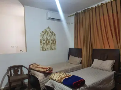 a bedroom with two beds and a chair in it at Alfares Hotel in At-Tafilah