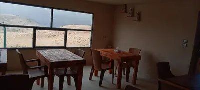 a dining room with two tables and chairs and a window at Alnwatif Gate guest house Dana nature reserve in Dana