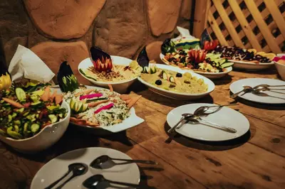 a table topped with bowls of food and plates of food at Wadi Rum Desert Dunes Luxury Camp in Wadi Rum