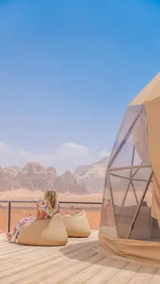 a little girl sitting on a pillow next to a tent at Charlotte luxury camp in Wadi Rum