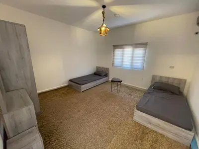a bedroom with two beds and a window at Wadi Al-Nakhil Hostel in Al Khuraybah
