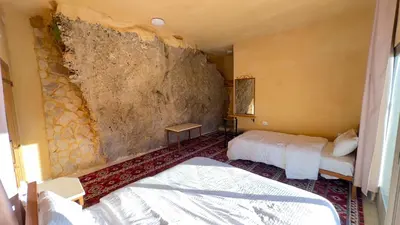 a bedroom with two beds and a stone wall at Wild Dana Eco Lodge- Hotel-Eco-Camp in Dana