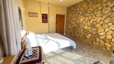 a bedroom with a bed and a stone wall at Wild Dana Eco Lodge- Hotel-Eco-Camp in Dana