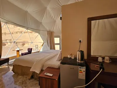 a bedroom with a bed and a large window at MAXIMAS LUXURY Wadi Rum in Wadi Rum