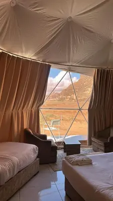 a bedroom with two beds and a large window at SELEN RUM LUXURY CAMP & Jeep Tours in Wadi Rum