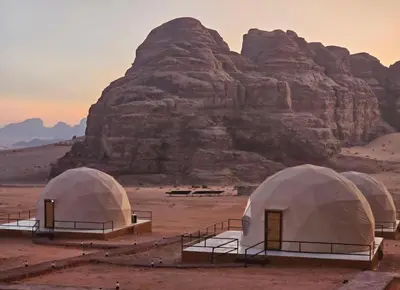 a group of tents in the desert with a mountain at Amazing Wadi Rum Camp in Wadi Rum