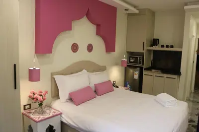 a bedroom with a large white bed with pink walls at Amman Trail Hotel & Studios in Amman