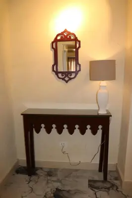 a table with a lamp and a mirror on a wall at Amman Trail Hotel & Studios in Amman