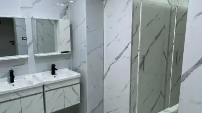 a bathroom with a shower and two sinks and a mirror at Amman Trail Hotel & Studios in Amman